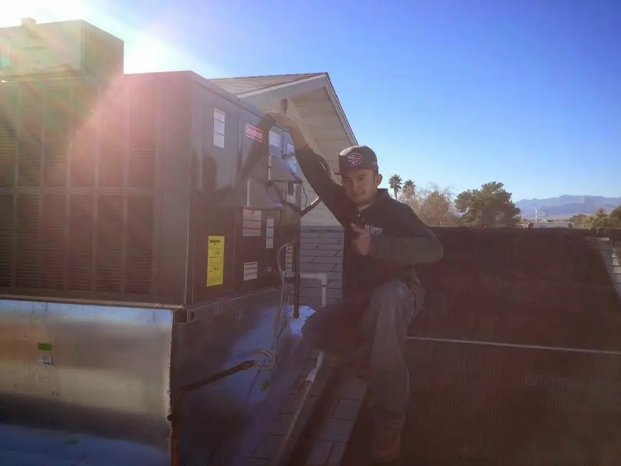 HVAC technician performing Air Duct Cleaning on a rooftop unit in Chalco