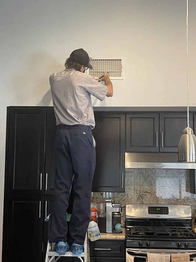 Technician inspecting an air vent during HVAC service in Chalco